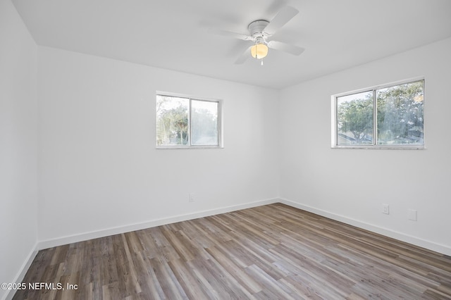 empty room featuring ceiling fan, baseboards, and wood finished floors