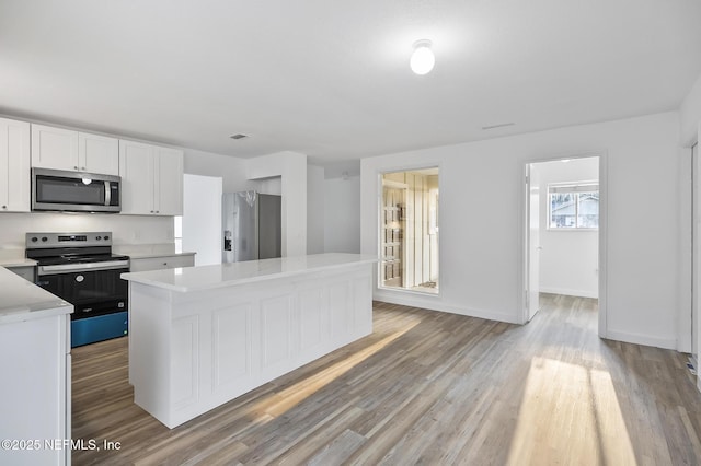 kitchen featuring a center island, light countertops, appliances with stainless steel finishes, light wood-style floors, and white cabinets