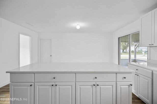 kitchen with dark wood-type flooring, white cabinets, and light stone countertops