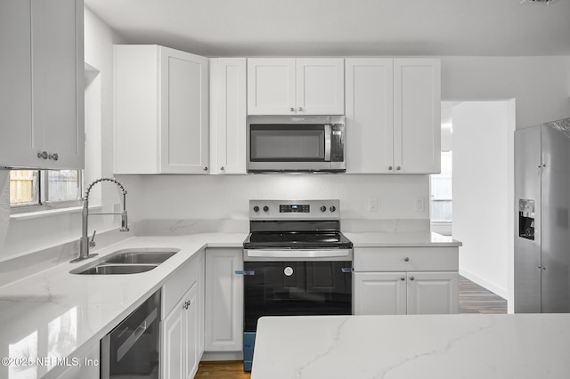 kitchen featuring appliances with stainless steel finishes, white cabinetry, and a sink