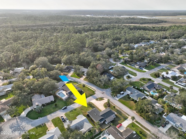 drone / aerial view featuring a wooded view and a residential view