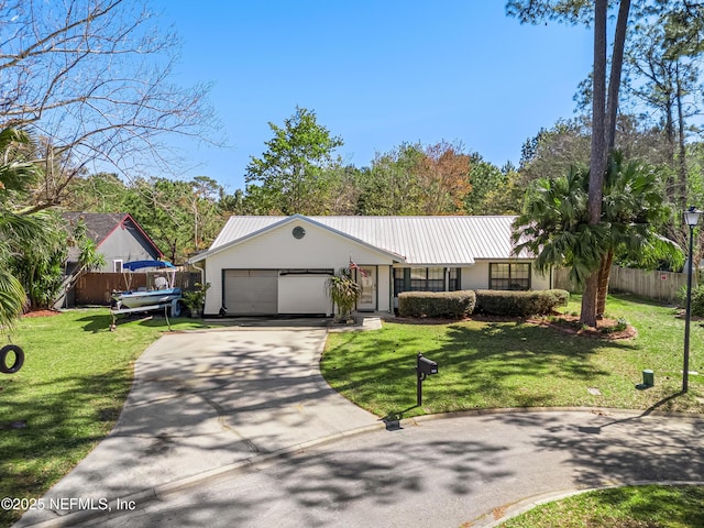 view of front of home with driveway, a garage, metal roof, fence, and a front lawn