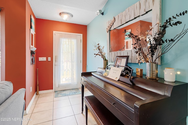 foyer entrance featuring light tile patterned floors, baseboards, and a textured ceiling