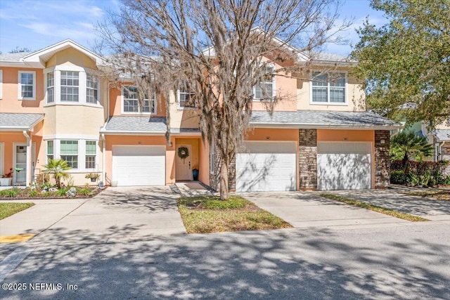 townhome / multi-family property featuring a garage, driveway, and stucco siding