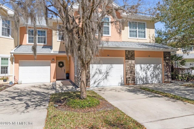 view of front of property featuring a garage, a shingled roof, concrete driveway, and stucco siding