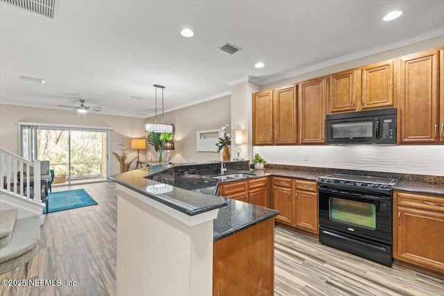 kitchen with black appliances, ornamental molding, visible vents, and light wood-style floors