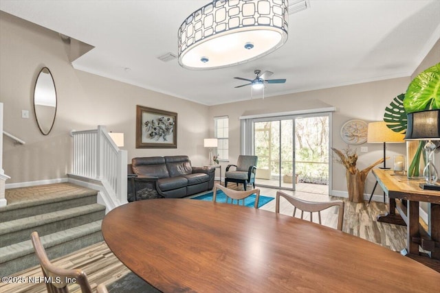 dining area featuring visible vents, stairway, crown molding, and wood finished floors