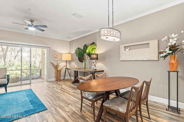 dining space with baseboards, ornamental molding, ceiling fan, and wood finished floors