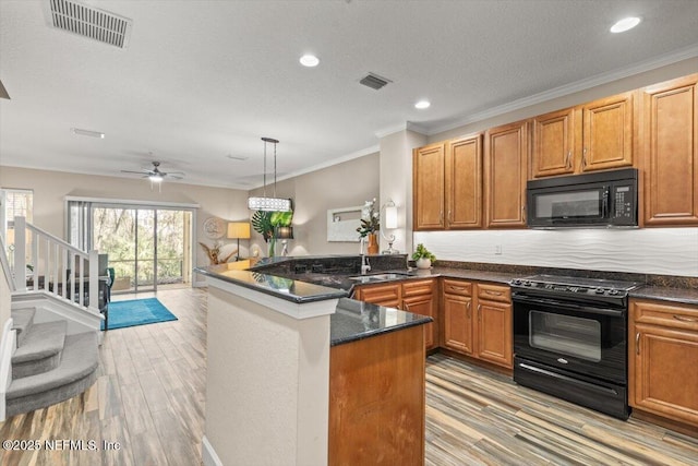 kitchen featuring a peninsula, black appliances, visible vents, and a sink