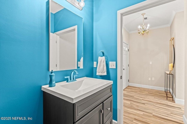 bathroom with baseboards, wood finished floors, crown molding, vanity, and a chandelier