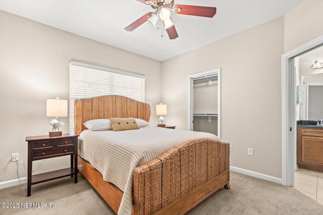 bedroom featuring light carpet, baseboards, a ceiling fan, a spacious closet, and a closet