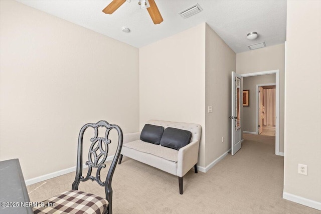 living area featuring light carpet, baseboards, visible vents, and a ceiling fan