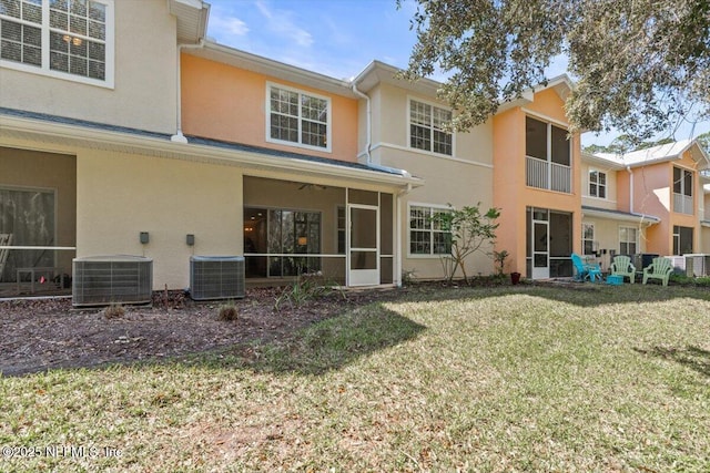 back of property featuring central air condition unit, a sunroom, a yard, and stucco siding