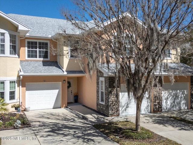 multi unit property with roof with shingles, stucco siding, concrete driveway, an attached garage, and stone siding