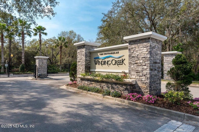 community / neighborhood sign featuring a gate and fence