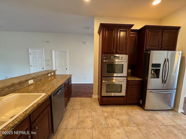 kitchen featuring recessed lighting, stainless steel appliances, stone counters, baseboards, and light tile patterned floors