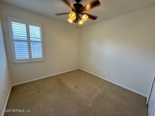 unfurnished room with a textured ceiling, a ceiling fan, baseboards, and carpet floors