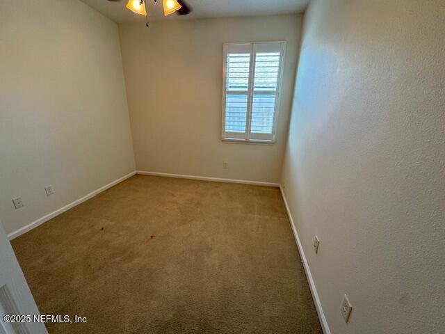 carpeted spare room with baseboards and a ceiling fan