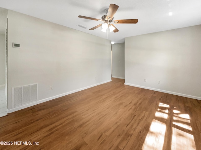 unfurnished room with wood finished floors, visible vents, and baseboards