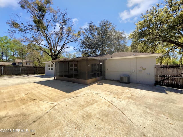 rear view of property with central air condition unit, fence, a patio, and a sunroom