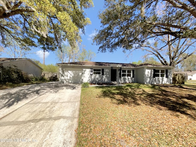 single story home featuring a garage, stucco siding, driveway, and a front lawn