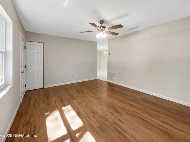 unfurnished room featuring visible vents, baseboards, wood finished floors, and a ceiling fan