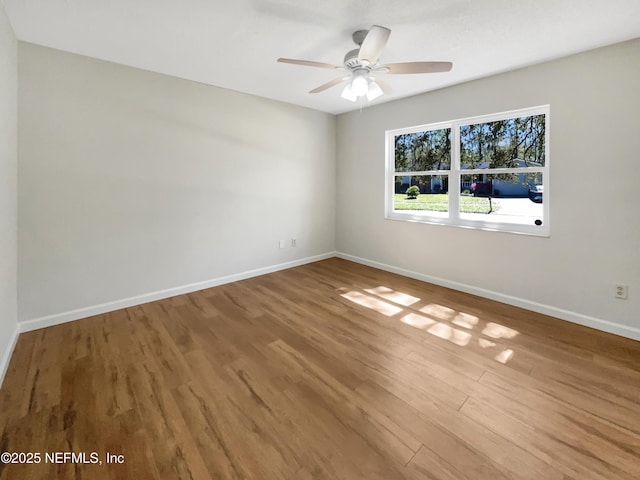 unfurnished room featuring a ceiling fan, wood finished floors, and baseboards