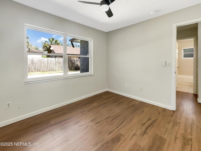 empty room with a ceiling fan, wood finished floors, and baseboards