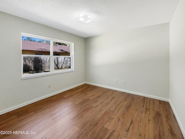 unfurnished room with a textured ceiling, baseboards, and wood finished floors