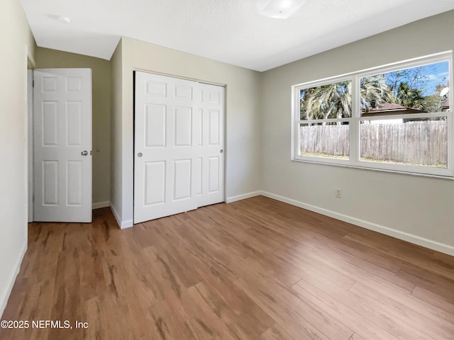 unfurnished bedroom with a closet, baseboards, and wood finished floors