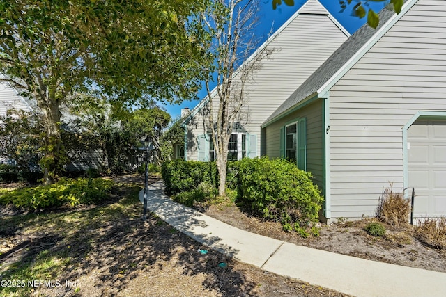 view of property exterior featuring a garage and a shingled roof