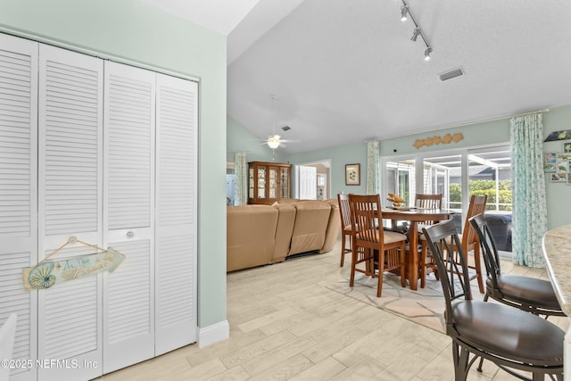 dining area with lofted ceiling, visible vents, rail lighting, a ceiling fan, and light wood-type flooring