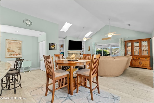 dining space with a skylight, visible vents, a ceiling fan, light wood-type flooring, and high vaulted ceiling