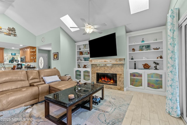 living area with ceiling fan, light wood-style flooring, a premium fireplace, and vaulted ceiling