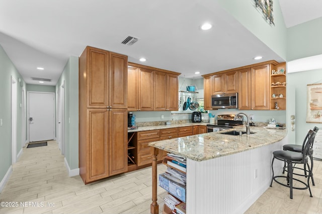 kitchen with a peninsula, visible vents, appliances with stainless steel finishes, open shelves, and brown cabinetry