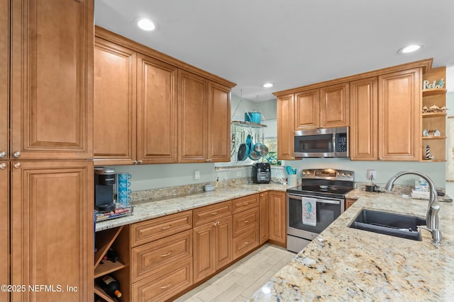 kitchen with light stone counters, stainless steel appliances, a sink, open shelves, and brown cabinetry