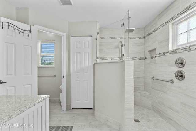 full bath featuring a walk in shower, a wealth of natural light, visible vents, and baseboards