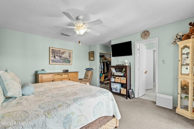 bedroom with a closet, visible vents, a ceiling fan, light carpet, and a textured ceiling