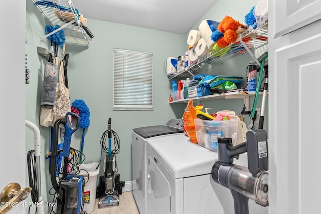 laundry room with laundry area, washing machine and dryer, baseboards, and wood finished floors