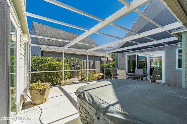 view of patio featuring glass enclosure and fence