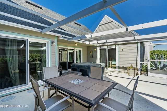 view of patio / terrace with outdoor dining area, glass enclosure, and a hot tub