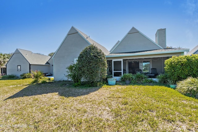 rear view of house with a sunroom, a yard, and a chimney