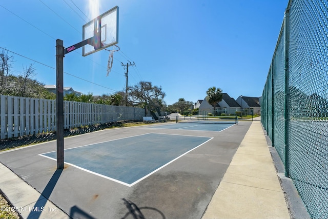 view of basketball court with a tennis court and fence