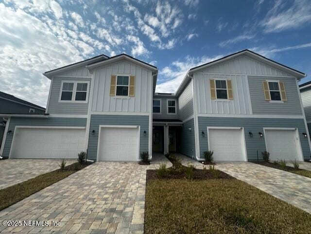 view of front of house with board and batten siding, an attached garage, and decorative driveway