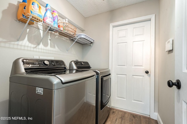 laundry room with wood finished floors, a textured ceiling, washing machine and dryer, and laundry area