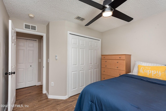 bedroom with a closet, visible vents, baseboards, and wood finished floors