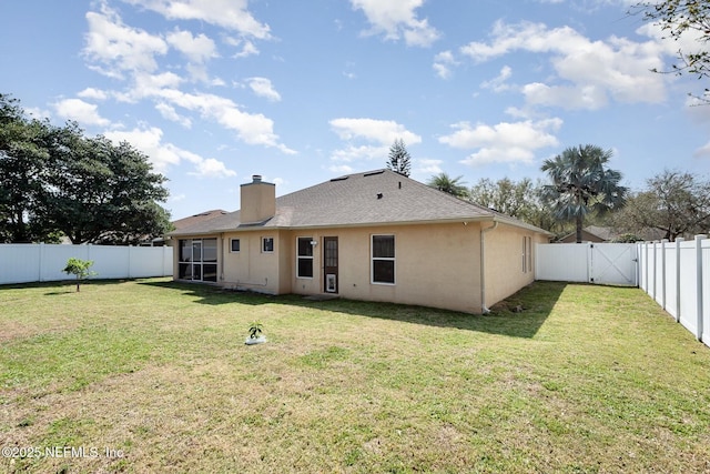 back of property with stucco siding, a lawn, a fenced backyard, and a gate