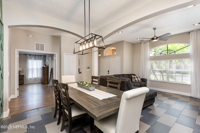 dining room featuring visible vents, baseboards, wood finished floors, arched walkways, and a textured ceiling