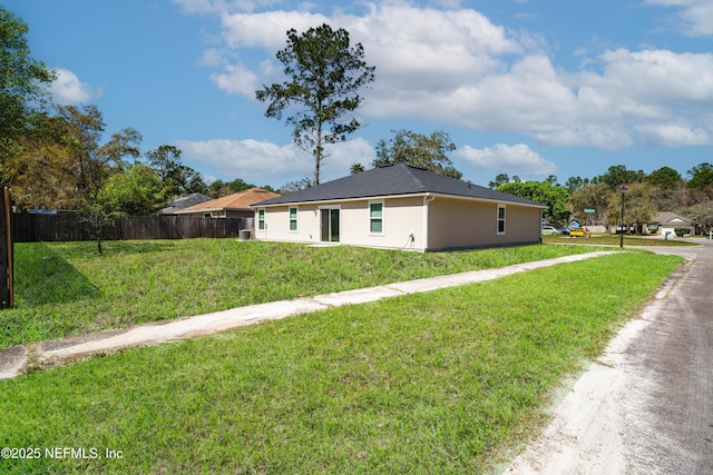 view of front of home with stucco siding, a front yard, and fence