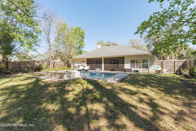 rear view of house with a lawn, a chimney, and a fenced backyard